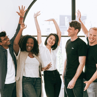 Diverse friends celebrate with their hands in the air smiling