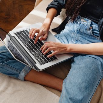 Person typing on a laptop sitting cross legged