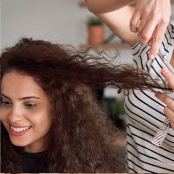 Woman with curly hair receiving a hair cut