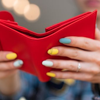 Woman with yellow and blue painted nails opening a red wallet
