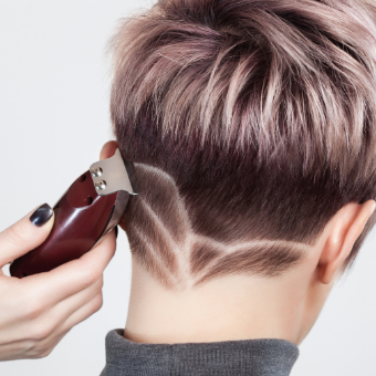 hairdresser makes a creative cut with a razor to a beautiful woman at the hairdresser